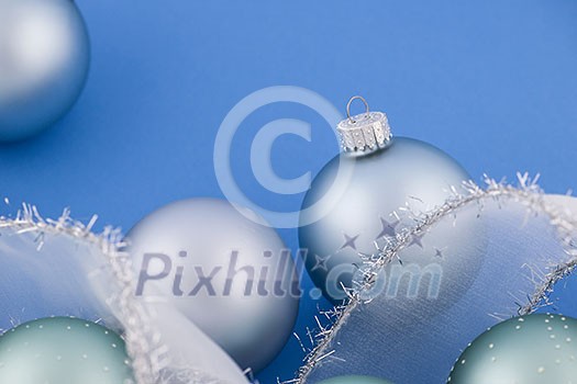Glass Christmas balls with holiday ribbon on blue background Glass Christmas balls with holiday ribbon on blue background