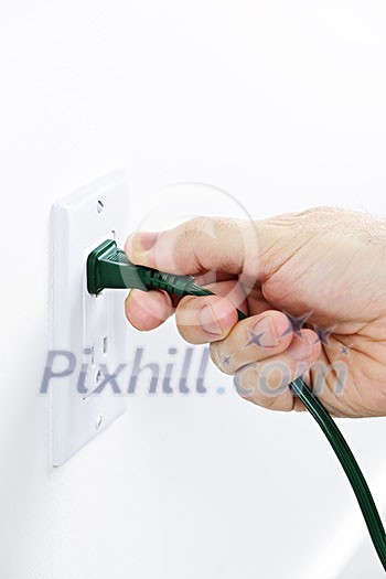 Hand pulling green electrical plug from outlet Hand pulling green electrical plug from outlet