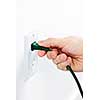 Hand pulling green electrical plug from outlet