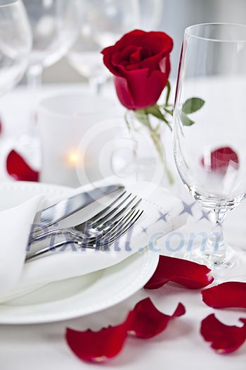 Romantic table setting with rose petals plates and cutlery Romantic table setting with rose petals plates and cutlery