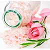 Pink bath salts in a glass jar with flowers and herbs