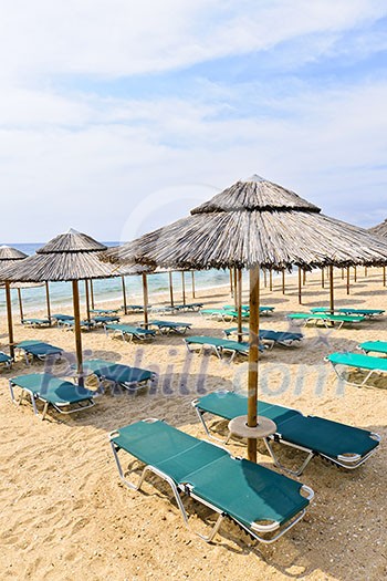 Straw umbrellas on empty seaside beach in Greece Straw umbrellas on empty seaside beach in Greece