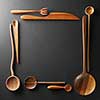 frame of wooden spoons, forks and a knife on black background