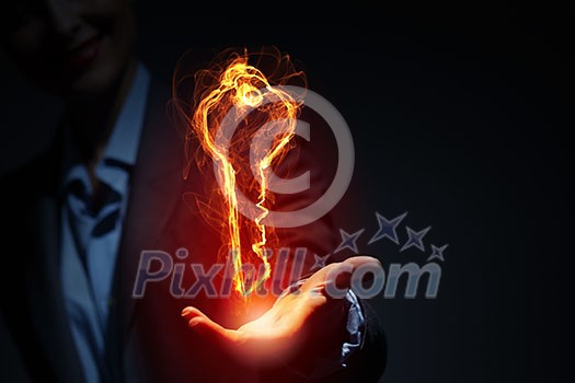 Glowing light key sign in palm on dark background Glowing light key sign in palm on dark background
