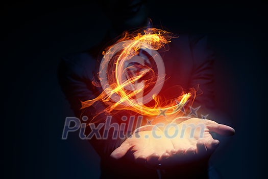 Burning euro sign in businessman palm on dark background Burning euro sign in businessman palm on dark background