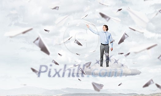 Young businessman in pile of books with paper plane in hand Young businessman in pile of books with paper plane in hand