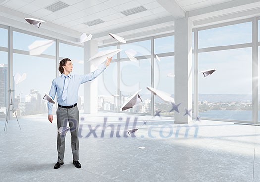 Young businessman in modern office with paper plane in hand Young businessman in modern office with paper plane in hand