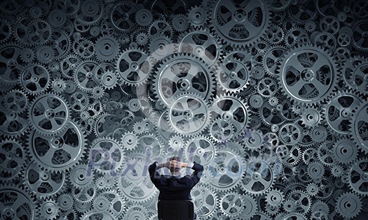 Young relaxed businessman sitting in chair and looking at gears mechanism Young relaxed businessman sitting in chair and looking at gears mechanism