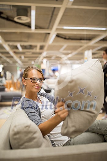 Pretty, young woman choosing the right furniture for her apartment in a modern home furnishings store (color toned image; shallow DOF) Pretty, young woman choosing the right furniture for her apartment in a modern home furnishings store (color toned image; shallow DOF)