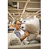 Pretty, young woman choosing the right furniture for her apartment in a modern home furnishings store (color toned image; shallow DOF)