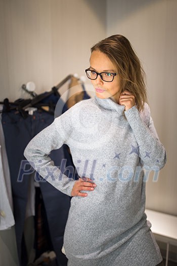 Young woman shopping in a fashion store, trying on some clothes she likes (color toned image; shallow DOF) Young woman shopping in a fashion store, trying on some clothes she likes (color toned image; shallow DOF)