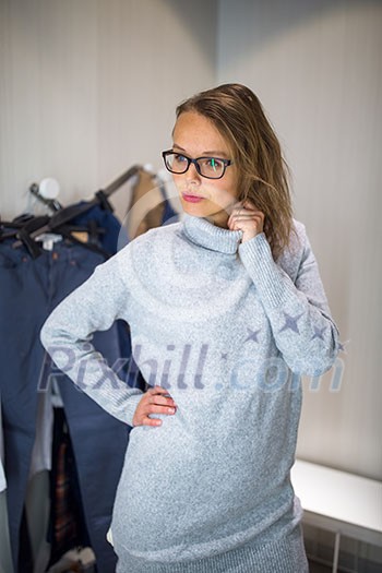 Young woman shopping in a fashion store, trying on some clothes she likes (color toned image; shallow DOF) Young woman shopping in a fashion store, trying on some clothes she likes (color toned image; shallow DOF)