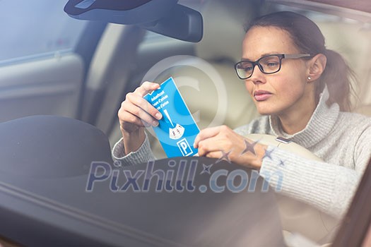 Pretty, young woman driving her new car - putting the necessary parking clock behind the windshield(color toned image; shallow DOF) Pretty, young woman driving her new car - putting the necessary parking clock behind the windshield(color toned image; shallow DOF)