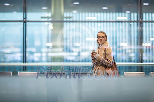 Young female passenger at the airport, using her tablet computer while waiting for her flight (color toned image) Young female passenger at the airport, using her tablet computer while waiting for her flight (color toned image)