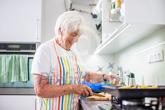 Senior woman/grandmother cooking in a modern kitchen (shallow DOF; color toned image) Senior woman/grandmother cooking in a modern kitchen (shallow DOF; color toned image)