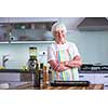 Senior woman cooking in the kitchen - eating and cooking healthy for her family; putting some potates in the oven, enjoying active retirement (shallow DOF; color toned image)