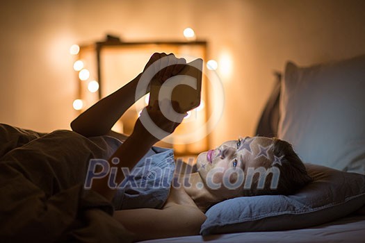Young woman using her tablet computer in her bed late at night (color toned image; shallow DOF) Young woman using her tablet computer in her bed late at night (color toned image; shallow DOF)