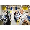 Pretty, young woman using self service checkout in a store (shallow DOF; color toned image)