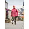 Senior woman walking her little dog on a city street; looking happy and relaxed (shallow DOF)