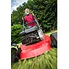 Senior man mowing the lawn in his garden (selective focus; shallow DOF)