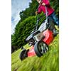 Senior man mowing the lawn in his garden