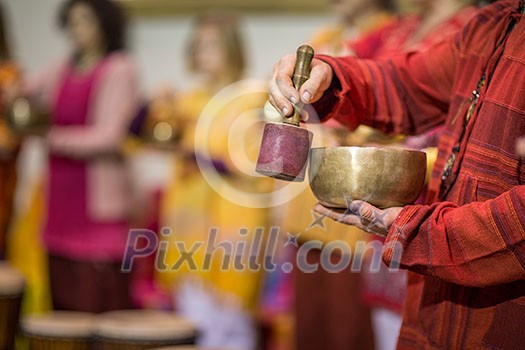 Man playing on a tibetian singing bowl (shallow DOF; color toned image) Man playing on a tibetian singing bowl (shallow DOF; color toned image)