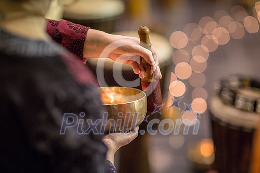 Woman playing on a tibetian singing bowl (shallow DOF; color toned image) Woman playing on a tibetian singing bowl (shallow DOF; color toned image)