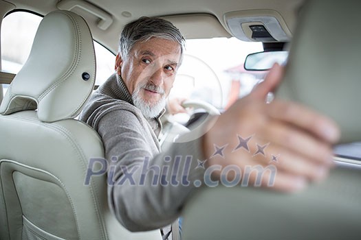 Senior drive driving his modern car, going in reverse, watching out not to hit anything or anyone (color toned image; shallow DOF) Senior drive driving his modern car, going in reverse, watching out not to hit anything or anyone (color toned image; shallow DOF)