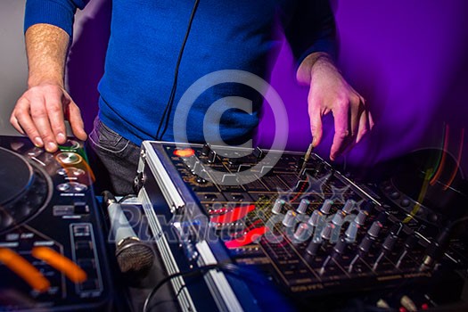 DJ's hands at the music mixer at a party - playing some fine songs for the guests (color toned image) DJ's hands at the music mixer at a party - playing some fine songs for the guests (color toned image)