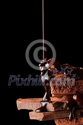 chocolate syrup being poured onto dark chocolate pieces isolated on black chocolate syrup being poured onto dark chocolate pieces isolated on black
