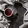 Knitted handmade wool clothing. Autumn or winter clothes and a cup of hot tea cup on a black background.