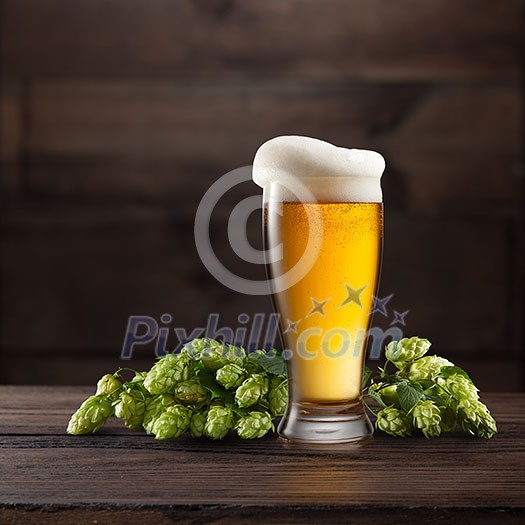 Still life with a keg of beer and green hop on a dark brown wooden background Still life with a keg of beer and green hop on a dark brown wooden background