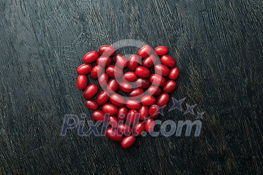 Red dogwood berries as a full heart shape isolated on black wooden background. Valentines day concept Red dogwood berries as a full heart shape isolated on black wooden background. Valentines day concept