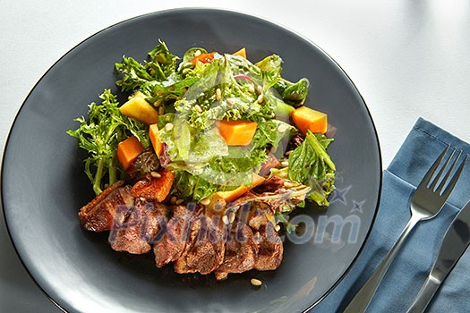 Overhead view of delicious, grilled meat duck with roasted pumpkin and fresh green herb salad on a plate Overhead view of delicious, grilled meat duck with roasted pumpkin and fresh green herb salad on a plate