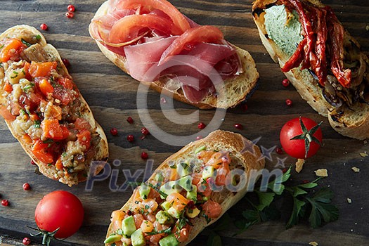 Italian bruschetta with roasted tomatoes, avocado, salmon, ham, peppers, herb on a wood board Italian bruschetta with roasted tomatoes, avocado, salmon, ham, peppers, herb on a wood board