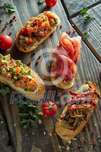 Italian crostini with various toppings on dark wood background, top view Italian crostini with various toppings on dark wood background, top view