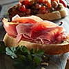 Italian bruschetta with parma ham on dark wooden background