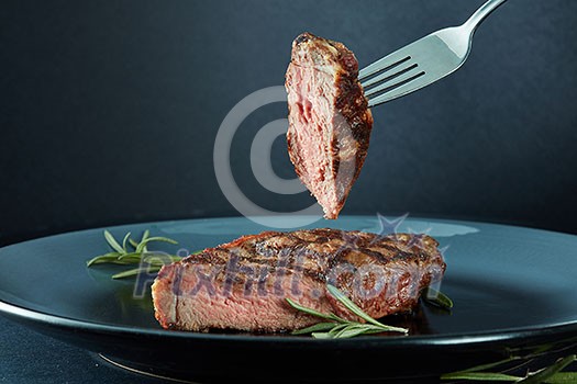 Juicy steak medium rare beef with spices and a piece of meat on a fork