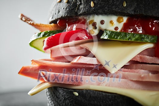Burger with ham and black bun, with lettuce and mayonnaise and ketchup on white background. Macro Burger with ham and black bun, with lettuce and mayonnaise and ketchup on white background. Macro
