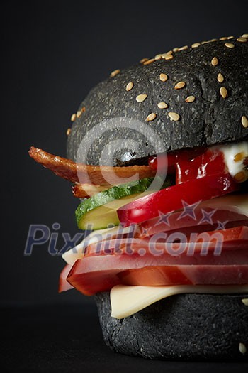 Gourmet black burger with Spicy sauce on black background Gourmet black burger with Spicy sauce on black background