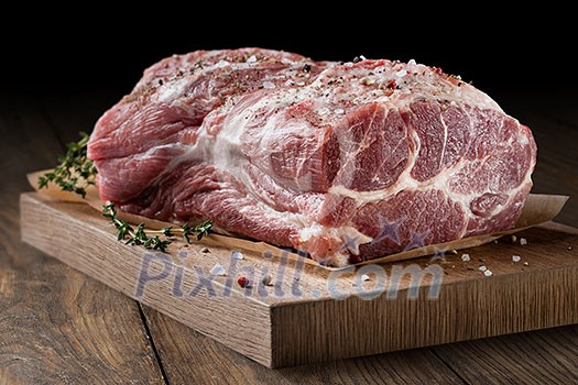 Photo of raw meat. Pork neck with herbs and green thyme on wooden board Photo of raw meat. Pork neck with herbs and green thyme on wooden board