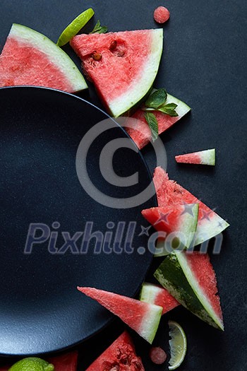 slices of watermelon placed in a circle of black plate slices of watermelon placed in a circle of black plate