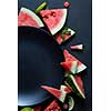 slices of watermelon placed in a circle of black plate