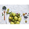 fresh plums and pears on a white plate on white background