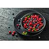 fresh berries in a black ceramic bowl on black background