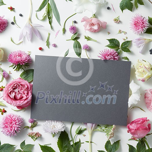 Beautiful pink and white flowers with empty dark notebook on a white background, copy space for your text Beautiful pink and white flowers with empty dark notebook on a white background, copy space for your text