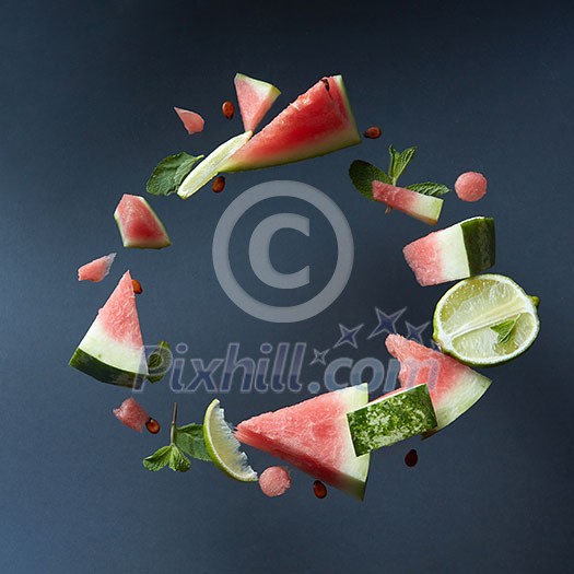 Slices of flying ripe juicy organic watermelon isolated on black , served with fresh lime and mint leaves. Watermelon mojito ingredients Slices of flying ripe juicy organic watermelon isolated on black , served with fresh lime and mint leaves. Watermelon mojito ingredients