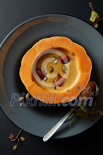 Cream of pumpkin soup with seeds on black background Cream of pumpkin soup with seeds on black background