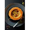Cream of pumpkin soup with seeds on black background