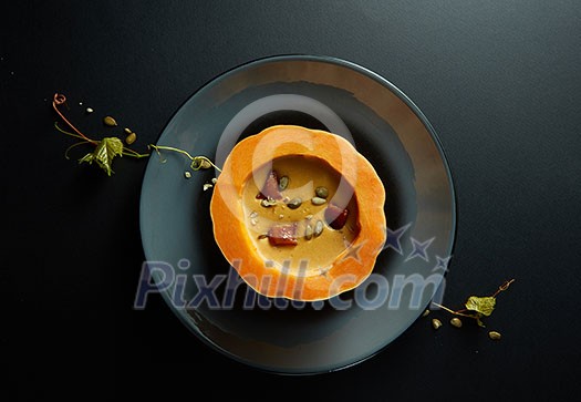 Organic red Uchiki kuri squash or Hokkaido pumpkin cream soup with parsley,on black background Organic red Uchiki kuri squash or Hokkaido pumpkin cream soup with parsley,on black background